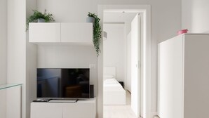 Eine moderne Küche mit integriertem Fernseher, weißen Schränken und einer Pflanze auf der obersten Ablagefläche.