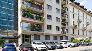 Ein mehrstöckiges Gebäude mit Balkonen, einem Parkplatz und einer modernen Glasfassade.