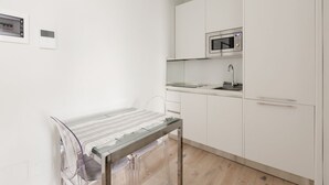Eine moderne Küche mit weißen Schränken, einer Mikrowelle und einem Glastisch.
