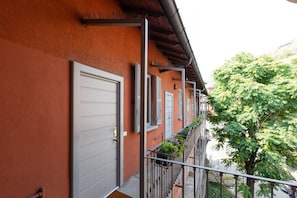 A building with a red facade, a white door, and a balcony with potted plants.