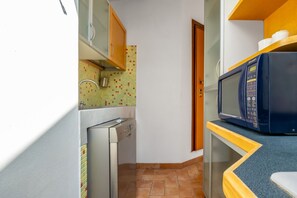 A compact kitchen with a dishwasher, microwave, and a tiled backsplash.