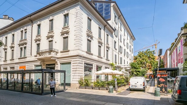 A historic building with a glass storefront, a covered outdoor seating area, and a parked van. - GuestHost - Bright APT Milan Garibaldi & Moscova! (Milano)