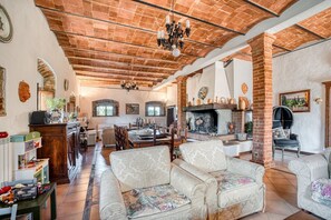 A spacious living area with a fireplace, comfortable seating, and a kitchen in the background.