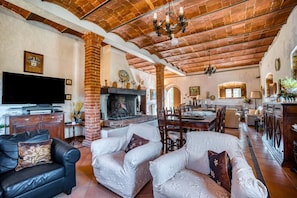 Un salón comedor amplio con chimenea, sofás de cuero y televisión.