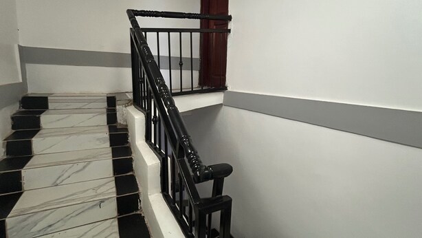 A staircase with black and white tiles, a black railing, and a wooden door.