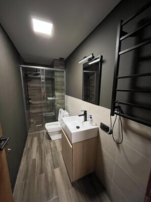 A modern bathroom with a glass shower enclosure, a white sink, and a towel rack. - Walk to Ski Lift-1BR-Studio-Balcony-Parking (Gudauri)