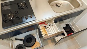 A kitchen with a stove, sink, and drawers containing pots, pans, and utensils. - LIVION V Hatagaya by Tranova (Tokyo)