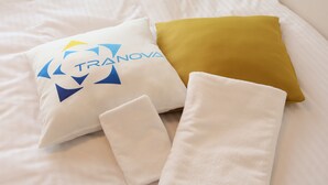 A bed with a white pillow, a mustard-colored pillow, and two white towels. - LIVION V Hatagaya by Tranova (Tokyo)