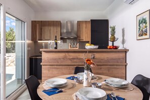 A modern kitchen with wooden cabinets, a central island, and a dining area with a table set for four. - Holiday Home Sole, Kostrena, Croatia (Kostrena)
