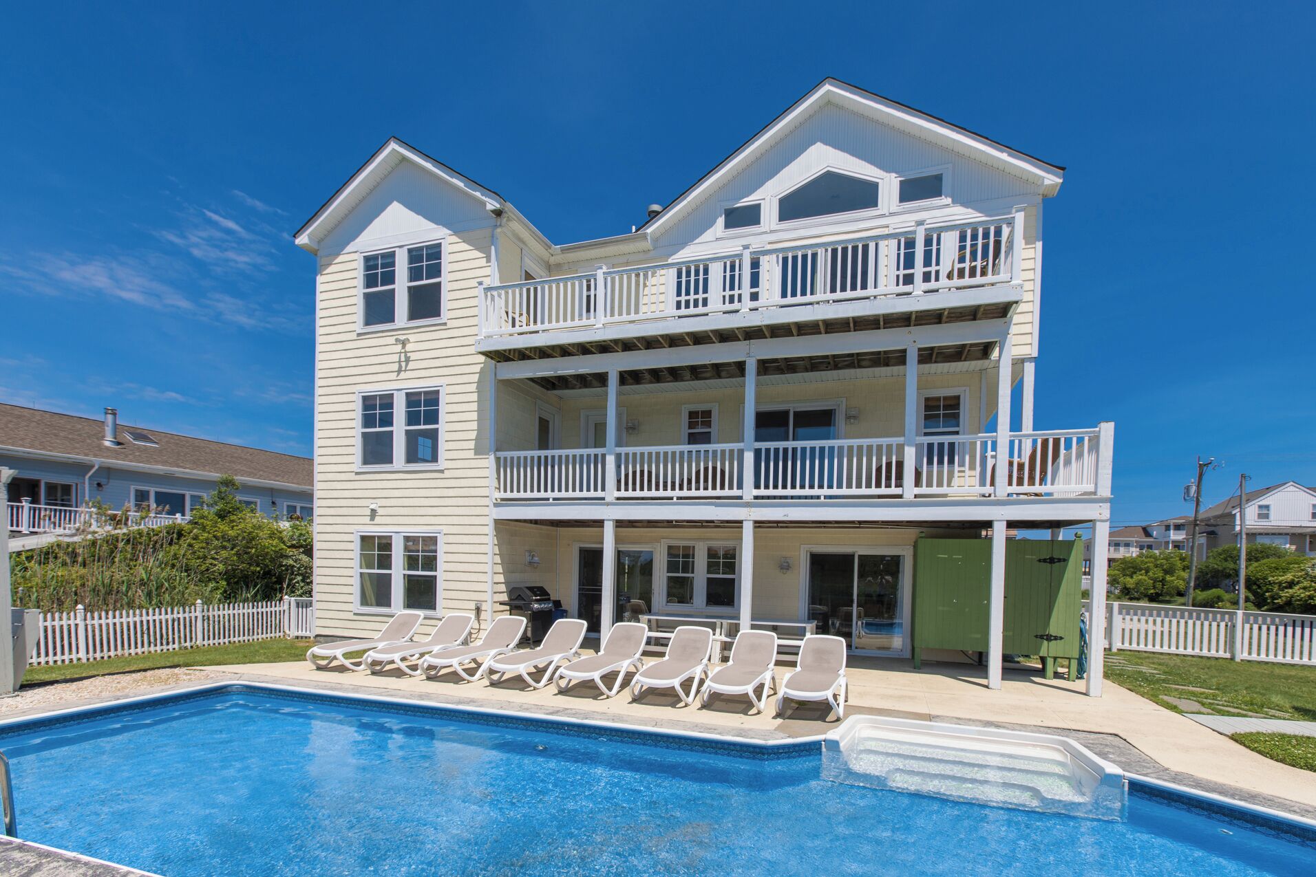 A two-story building with a swimming pool and sun loungers.