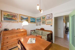 A dining area with a wooden table, a sofa, and a lamp. - Casa De Nardis Sunny House, Riva del Garda, Italy (Riva del Garda)