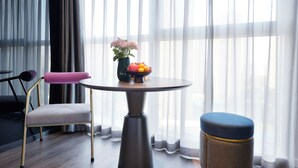 A modern room with a round table, a cushioned chair, a small stool, and a vase with flowers. - Mei Hao Li Jinhui Square sto (Xi'an)