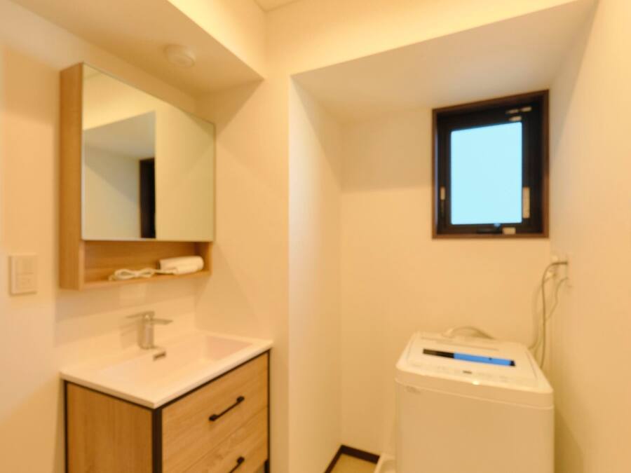 A bathroom with a sink, mirror, and a small window.