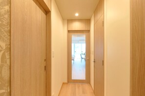 Un couloir étroit avec des portes en bois et un luminaire au plafond.