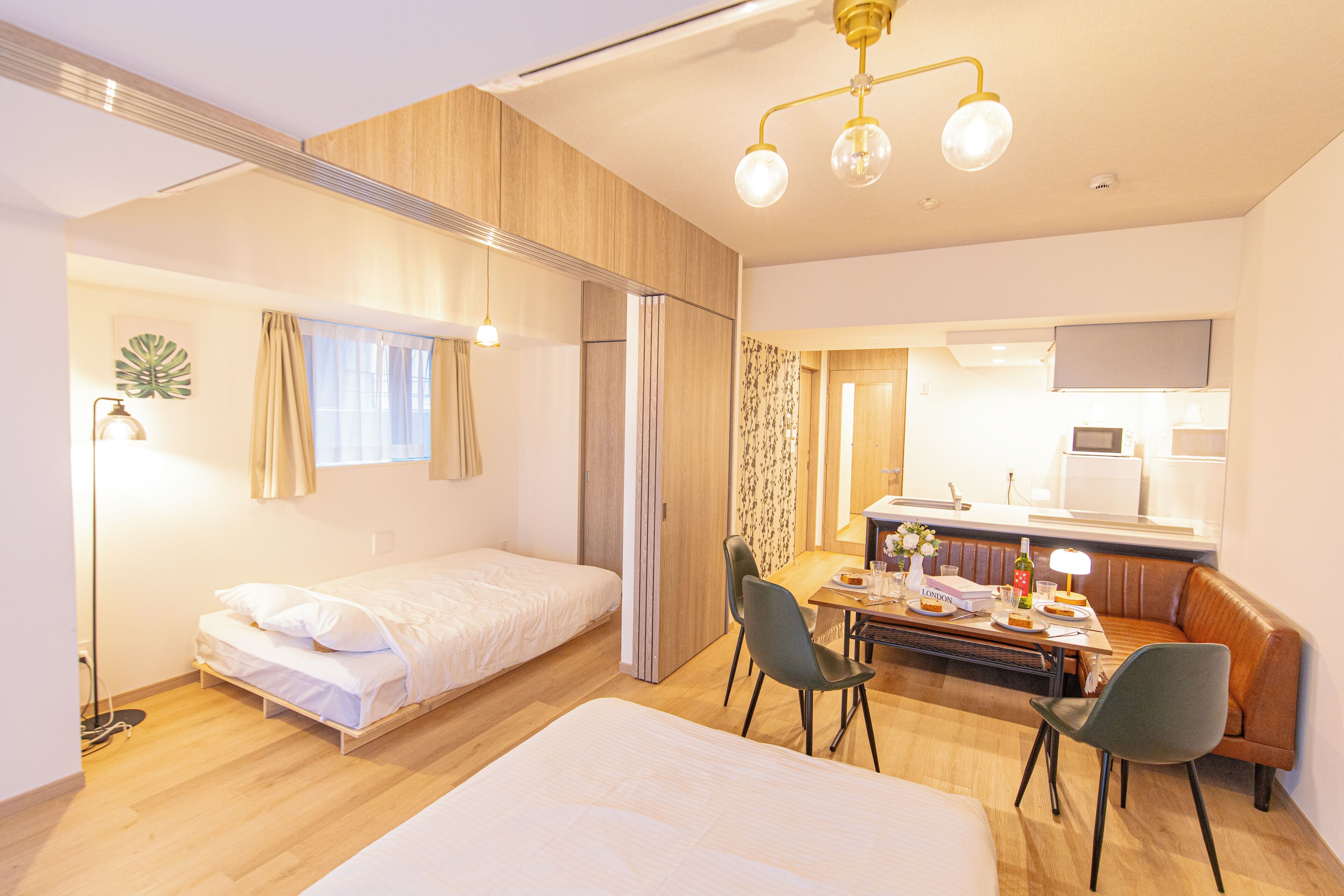 Una habitación de hotel compacta con cama, escritorio, silla y kitchenette.