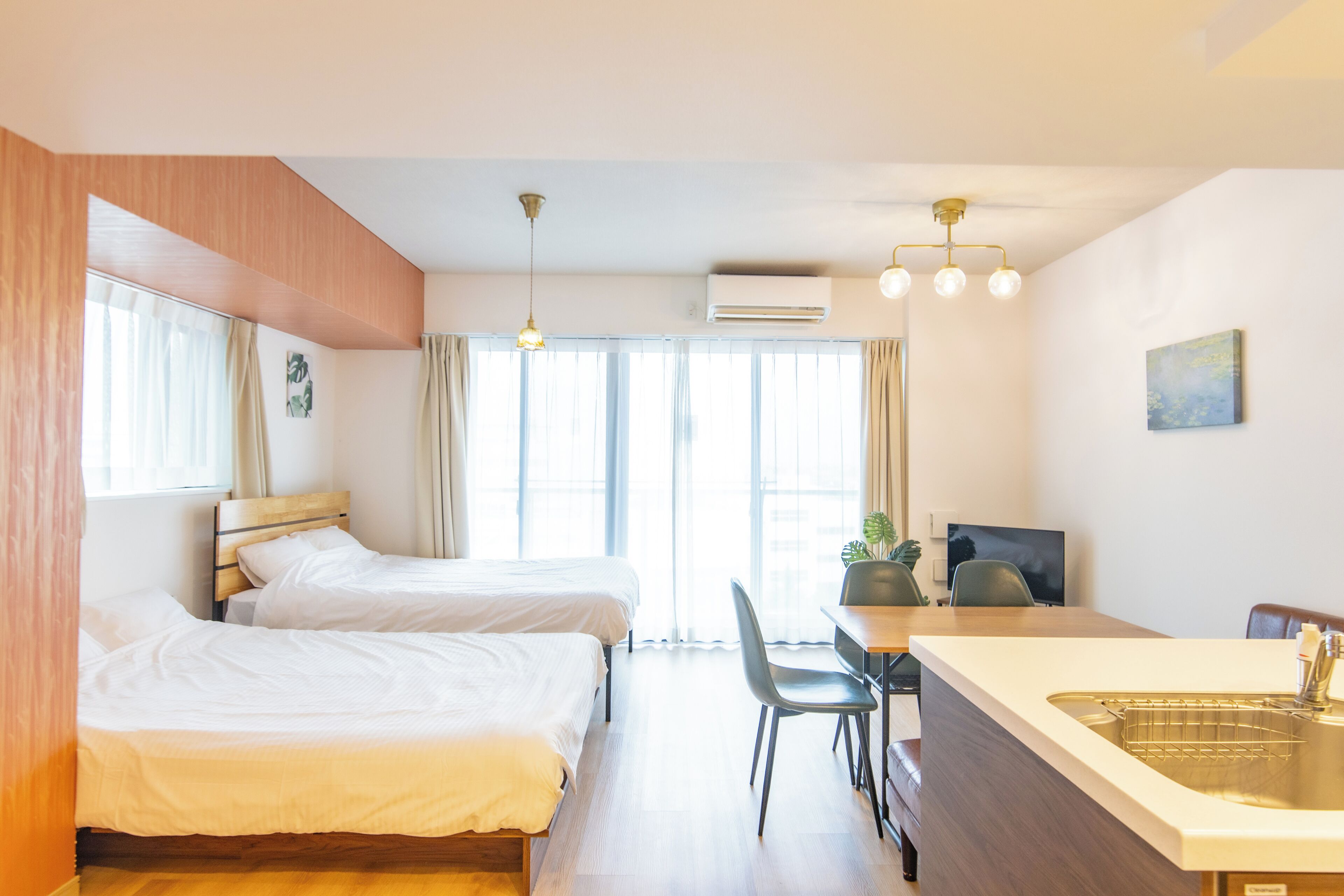 A hotel room with two beds, a desk with a chair, a sink, and a television.