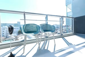 Un balcon avec deux chaises et un lampadaire, donnant sur un paysage urbain.