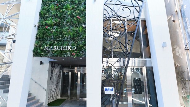 A modern building entrance with a green vertical garden, a marble wall, and a metal gate. - MODELLO Sangenjaya by Tranova (Tokyo)