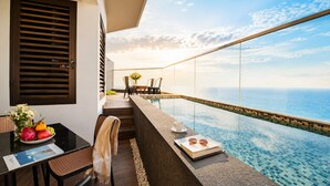 Un balcón con vista al océano, una mesa de comedor con sillas y una piscina pequeña.
