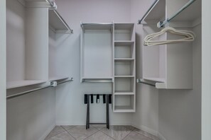 Ein begehbarer Kleiderschrank mit offenen Regalen, einem Kleiderständer und einer Kleiderstange.