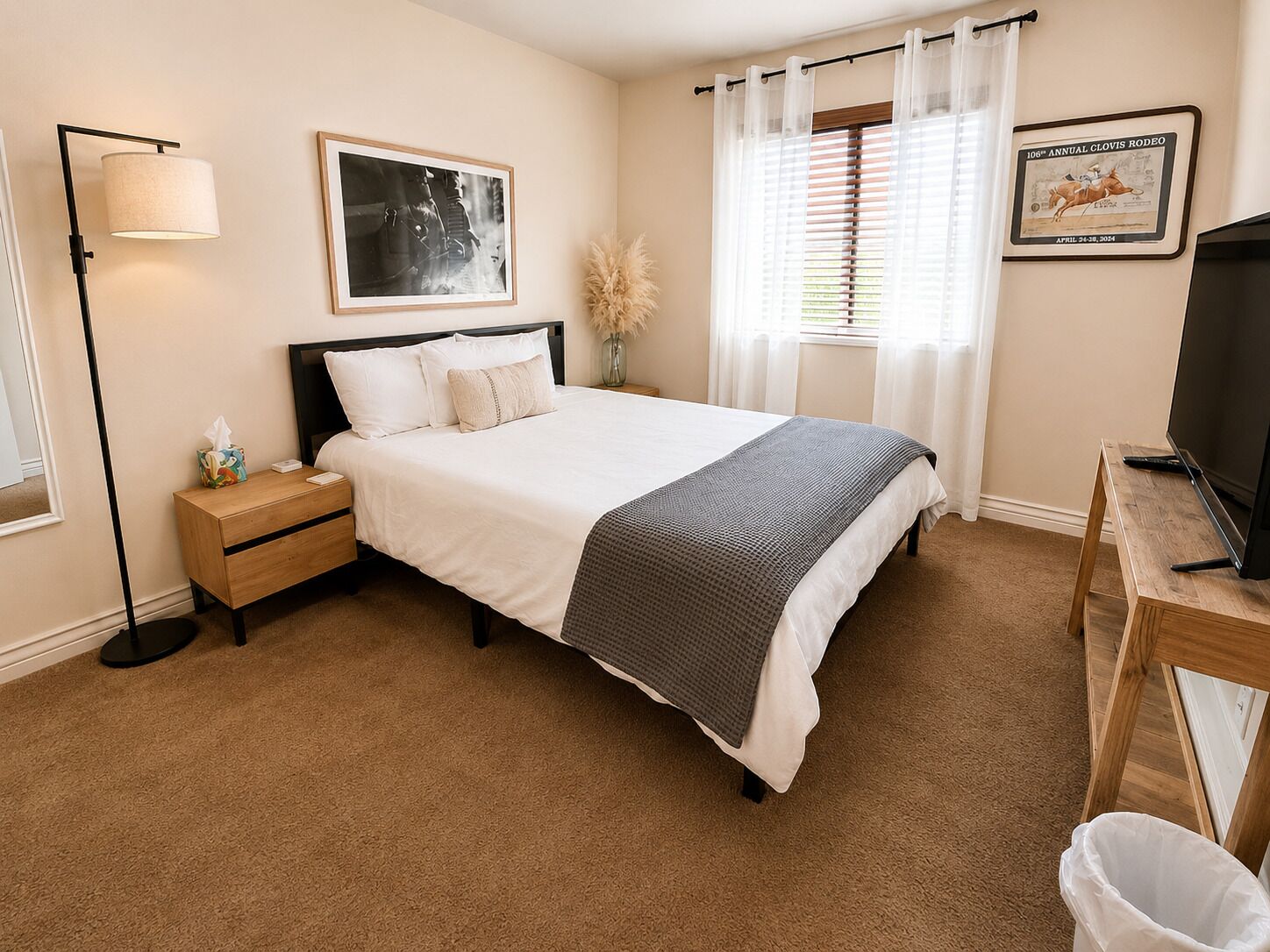 A neatly arranged bedroom with a bed, bedside table, lamp, and a framed picture on the wall.
