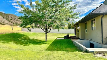 Une maison avec une pelouse bien entretenue, un arbre et un espace patio.