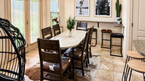 A dining area with a round table, chairs, a chandelier, and framed pictures on the wall.