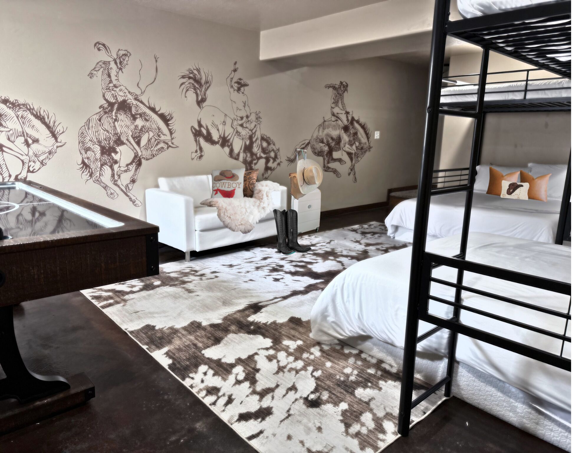 Een kamer met stapelbedden, een witte bank, een kamerkleed met een patroon en wanddecoratie.