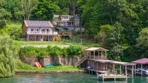 Une maison au bord du lac, avec une terrasse, un quai et un bateau.