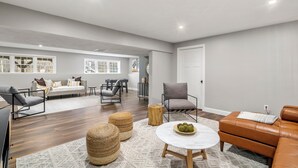 A spacious living room with a sofa, armchairs, a coffee table, and a dining area with a table and chairs. - Cozy Chic Countryside Haven -  Sleeps 4 , Firepit (Sturbridge)