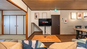 A modern interior with a flat-screen TV, wooden flooring, tatami mats, and a dining area. - TACHIBANA Tengachaya (Osaka)