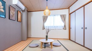 A traditional Japanese room with tatami flooring, a low table with cushions, a hanging light fixture, and sliding doors. - TACHIBANA Tengachaya (Osaka)