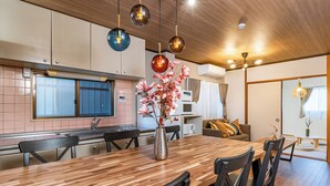 A modern kitchen with a wooden dining table, black chairs, and a vase with flowers. - TACHIBANA Tengachaya (Osaka)