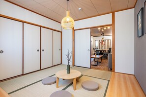 Una habitación japonesa tradicional con suelo de tatami, una mesa de madera baja y una lámpara colgante.
