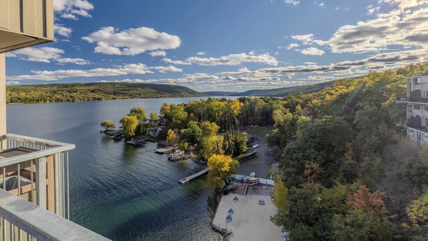 A lakeside property with a dock, boats, and a view of the surrounding forest and hills. - Beautiful 3-bed home with Canandaigua Lake view and access, Bristol Ski, Winery (Canandaigua)
