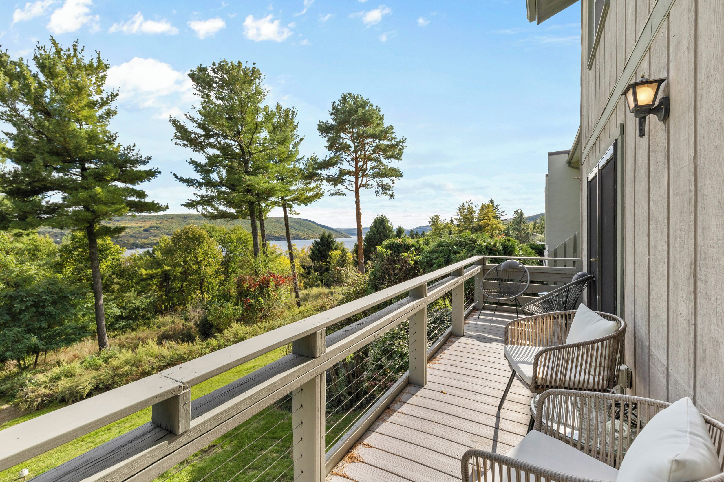 Eine Holzterrasse mit Gartenmöbeln und Geländer mit Blick auf eine natürliche Landschaft.