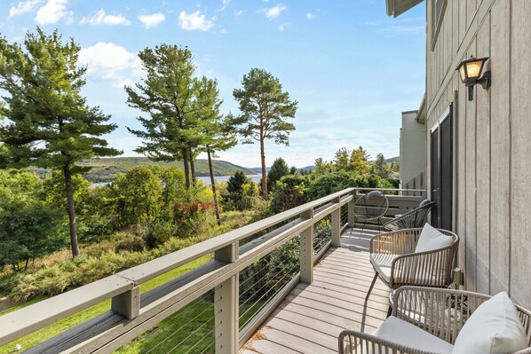 A wooden deck with outdoor furniture and a railing overlooking a natural landscape.