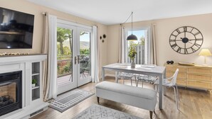 A modern living room with a fireplace, television, dining area, and a large clock on the wall. - Beautiful 3-bed home with Canandaigua Lake view and access, Bristol Ski, Winery (Canandaigua)
