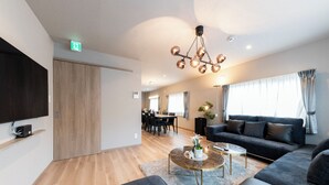 A modern living room with a sofa, coffee table, and a TV mounted on the wall. - THE COMFY SAPPORO (Sapporo)