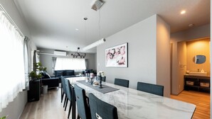 A modern dining area with a marble table, dark chairs, and a large window with curtains. - THE COMFY SAPPORO (Sapporo)