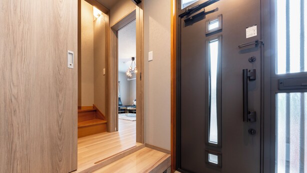 A modern hallway with wooden flooring, a dark door with a handle, and a small window. - THE COMFY SAPPORO (Sapporo)