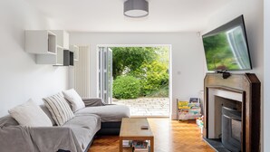 Una sala de estar moderna con un sofá, una mesa de centro, una chimenea y un televisor montado en la pared.