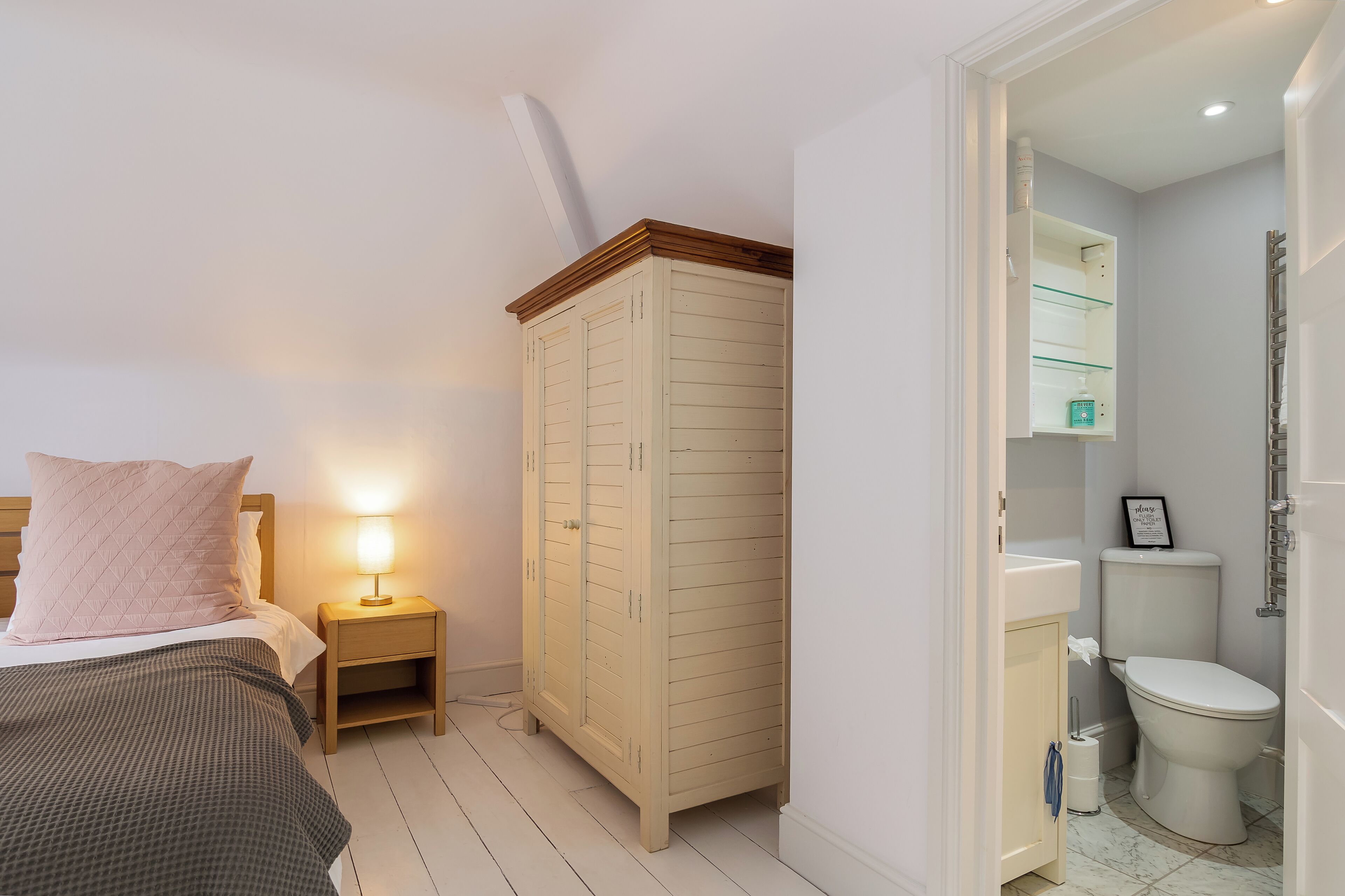 Une chambre à coucher comprenant un lit, une table de chevet, une armoire et une salle de bain avec des toilettes et un lavabo.