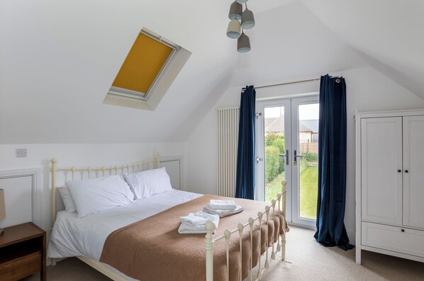 A bedroom with a bed, a window, a wardrobe, and a door leading to a balcony. - Stunning 5 Bed in the Centre of Bourton (Cheltenham)