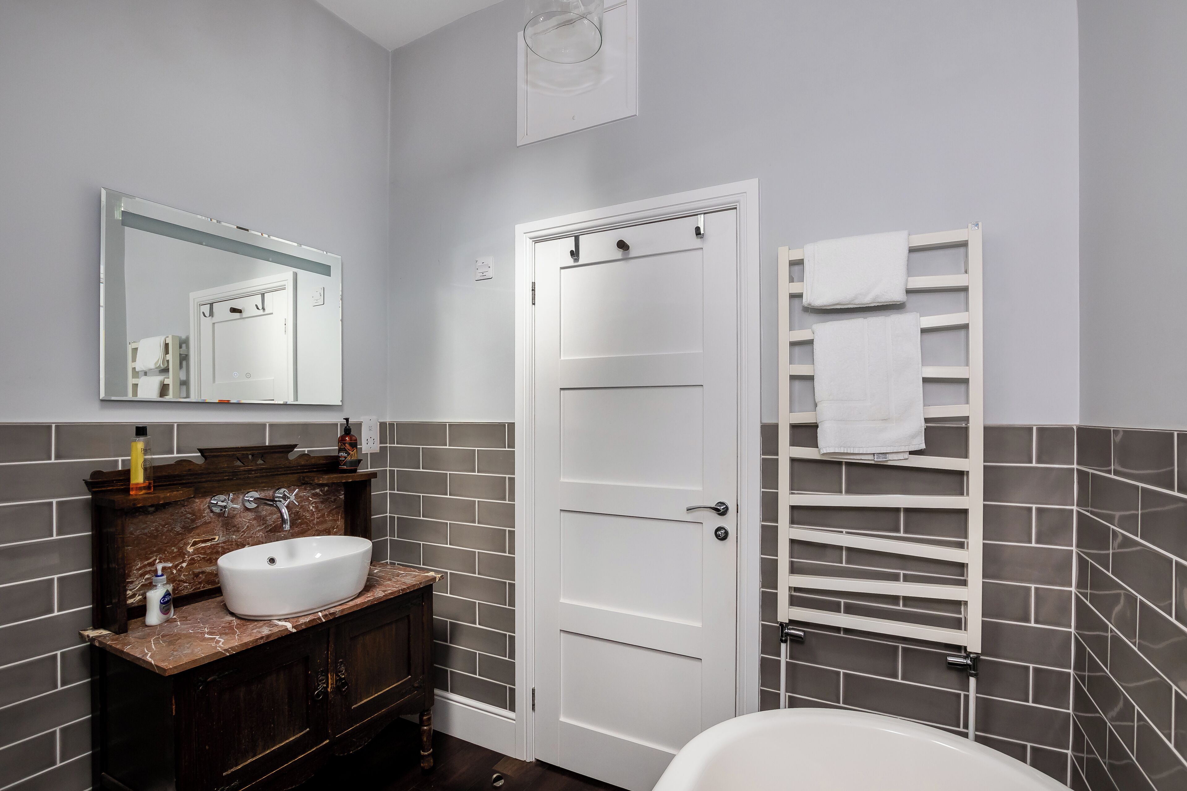 A bathroom with a white sink, dark wooden vanity, a white door, and a towel rack.