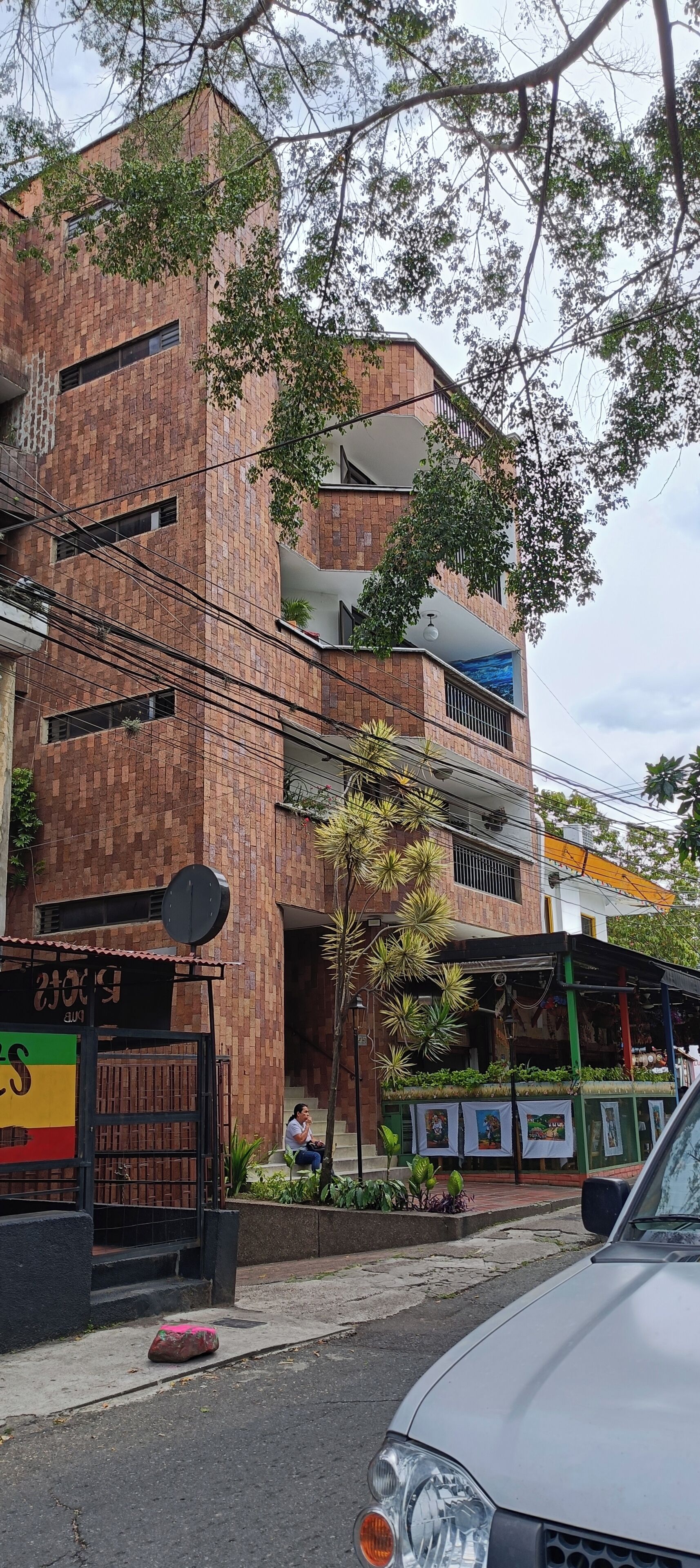 Un immeuble à plusieurs étages, doté d’une façade en briques, de balcons et d’un petit arbre devant l’entrée.