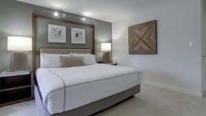 A modern hotel room with a large bed, two bedside tables with lamps, and two framed artworks on the wall.