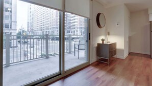 A modern apartment with large sliding glass doors, a small wooden cabinet, and a round mirror on the wall.