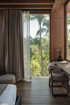 Ein Zimmer mit Bett, Schreibtisch und Blick auf Palmen.