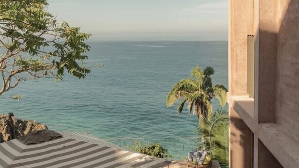 A patio with a table set for dining, overlooking a body of water.